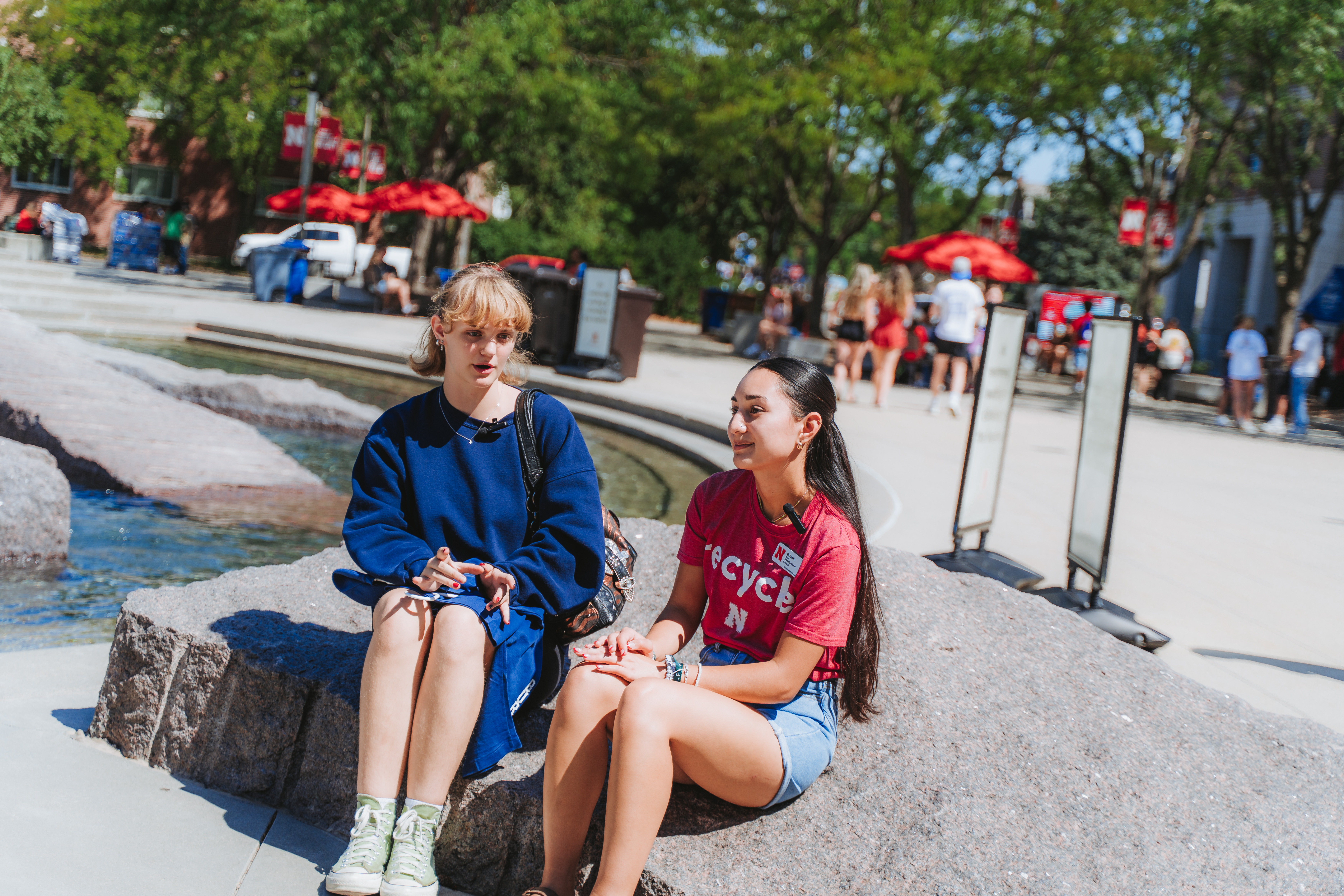 Sustainability Ambassador Mia sits with another student talking about the Big Thread Welcome event