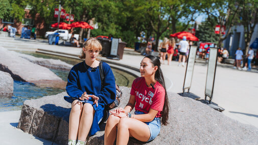 Sustainability Ambassador Mia sits with another student talking about the Big Thread Welcome event