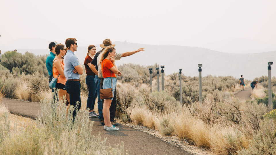 Students standing outside by prairie pointing at distance