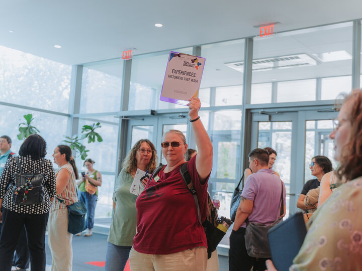 Group leader at the 2025 All-Staff Conference holds up the experience sign for the historic tree tour.
